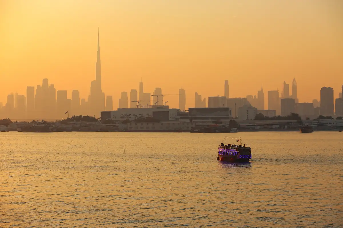 Dubai skyline in silhouette at golden hour, seen across the water from a boat